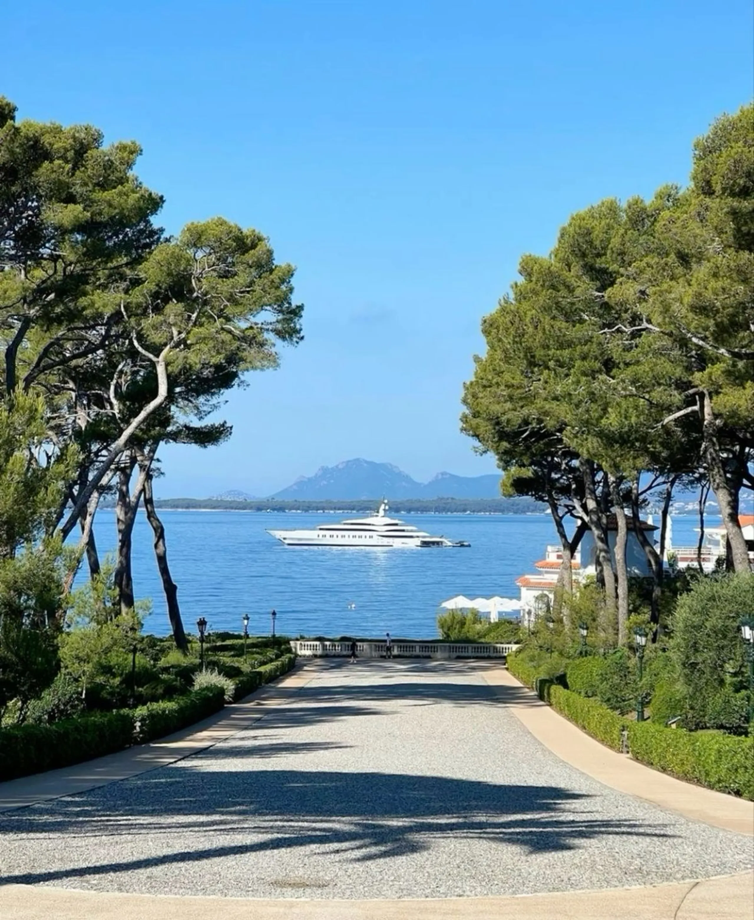 Luxury yacht anchored off a pine-lined French Riviera estate