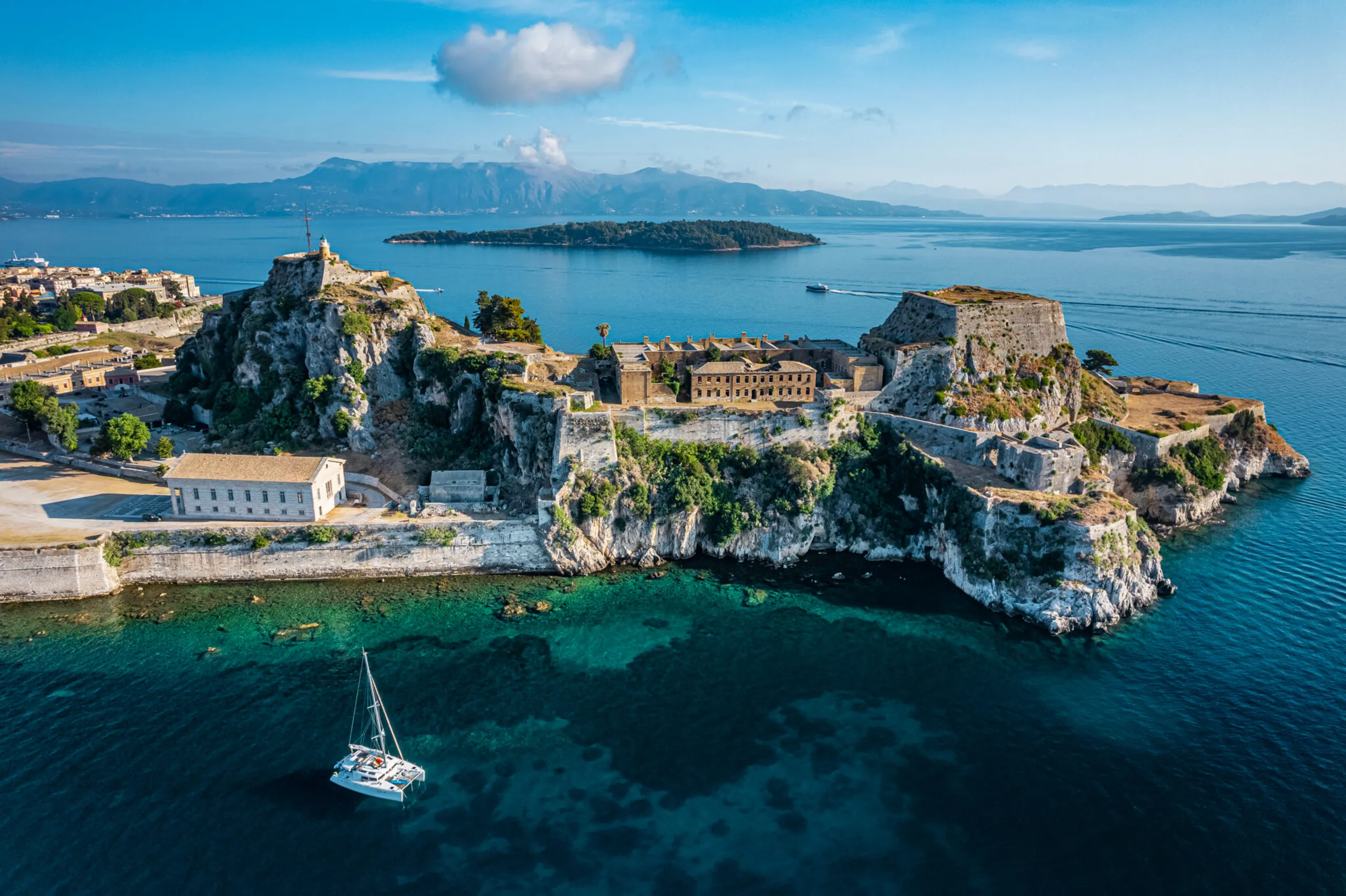 Corfu Old Fortress overlooking turquoise water and a sailing yacht in the Ionian Sea