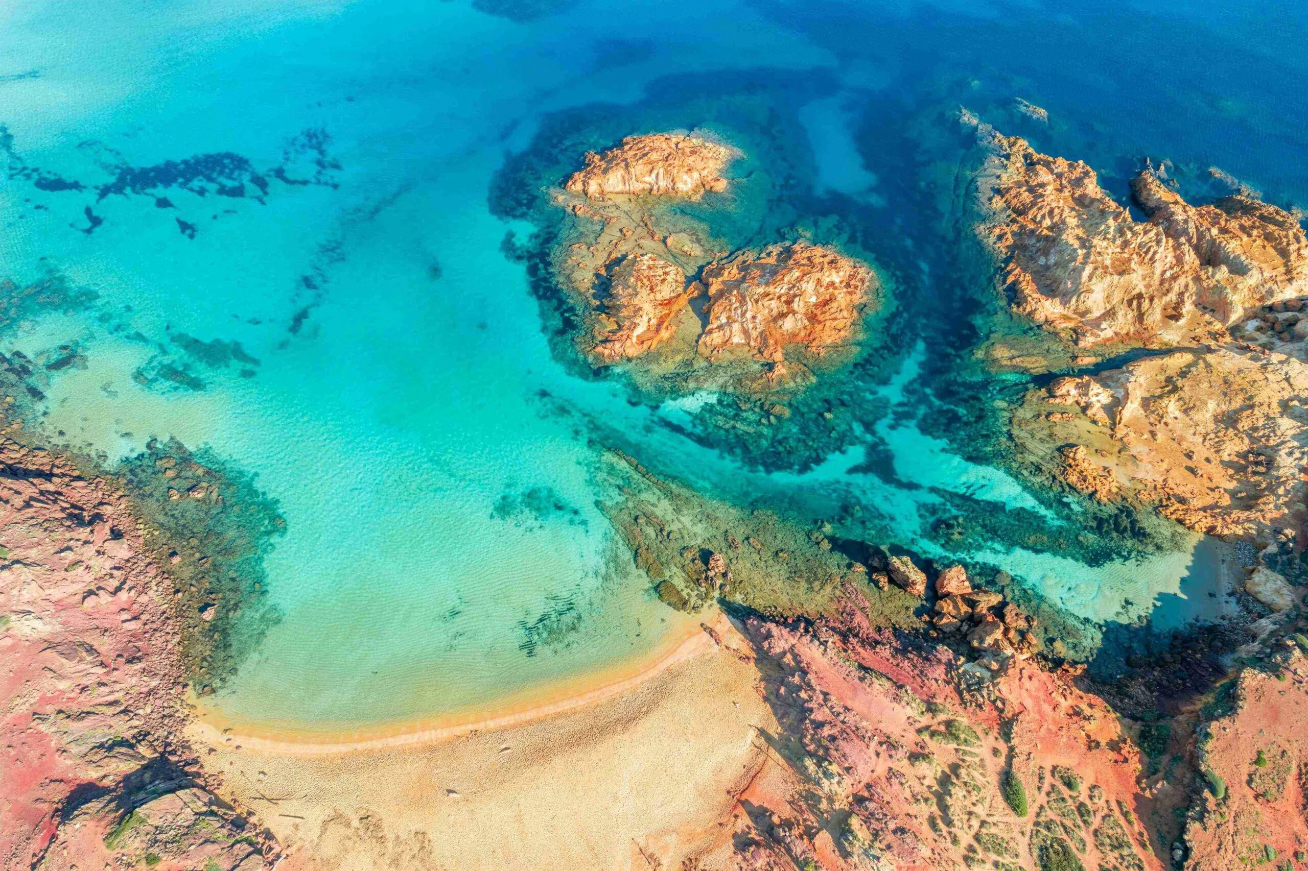 Aerial view of Cala Pregonda in Menorca with turquoise water and rocky coastline