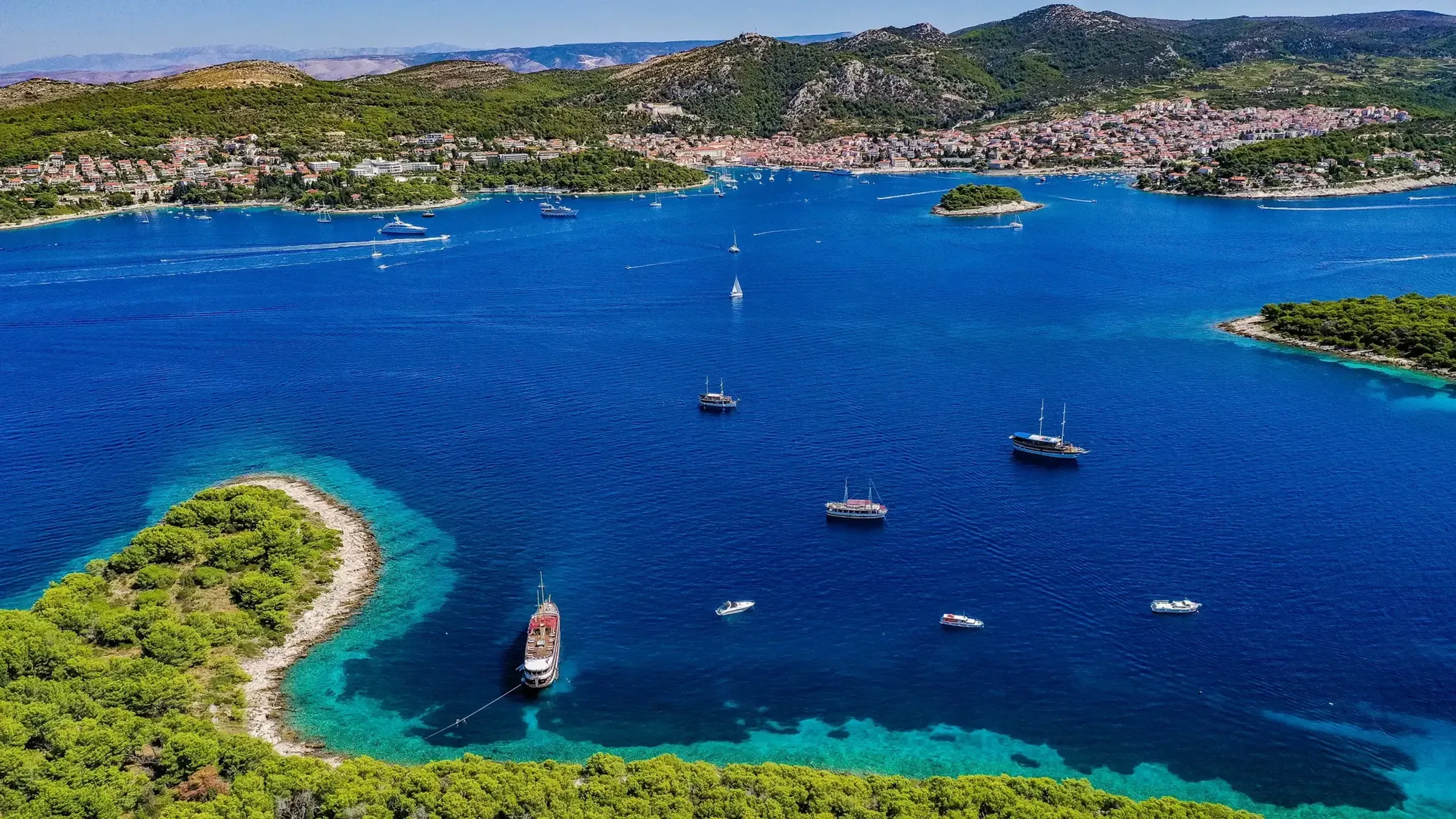 Aerial view of boats anchored in the blue waters near Hvar with the coastline and town in the background