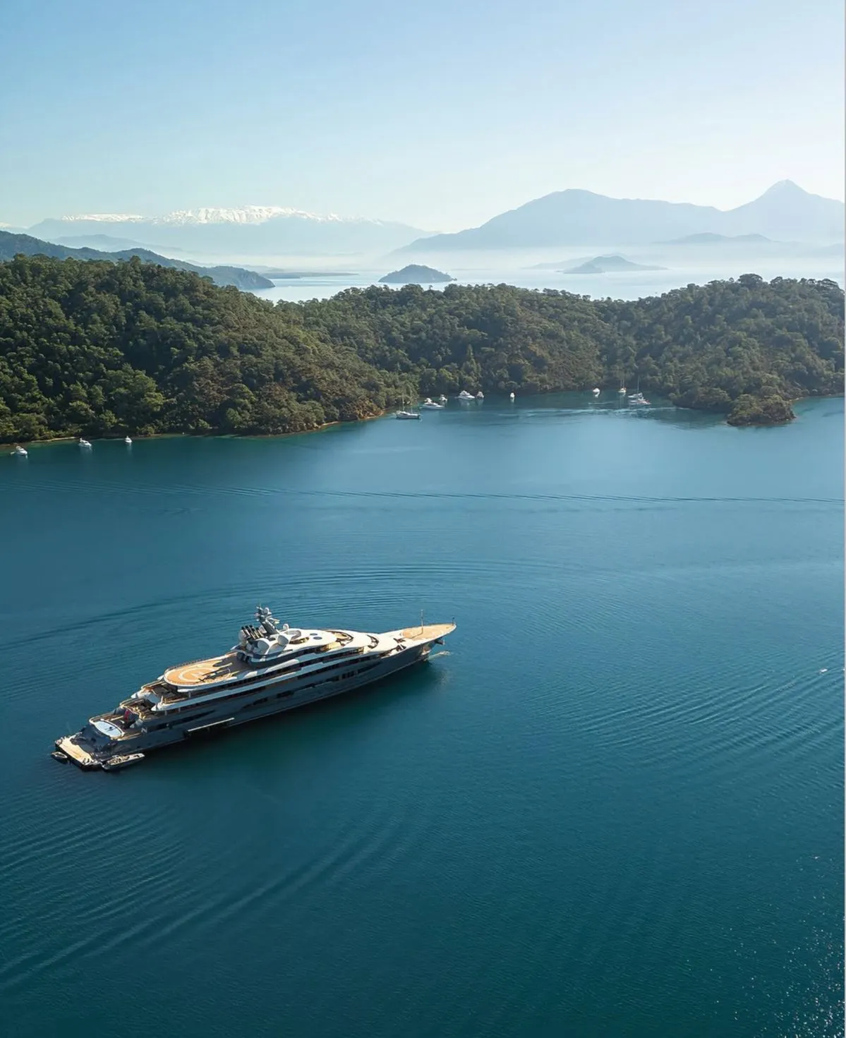 Superyacht cruising through a calm island bay as part of a bespoke yacht charter route