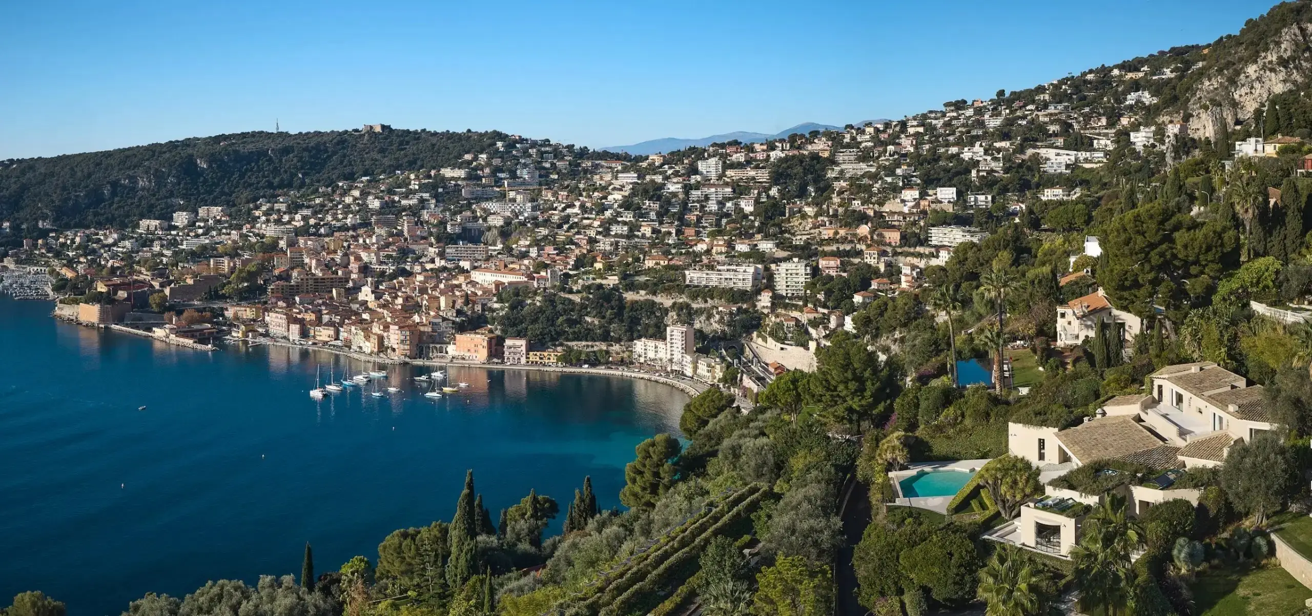 A superyacht at anchor in a quiet Riviera cove near Monaco