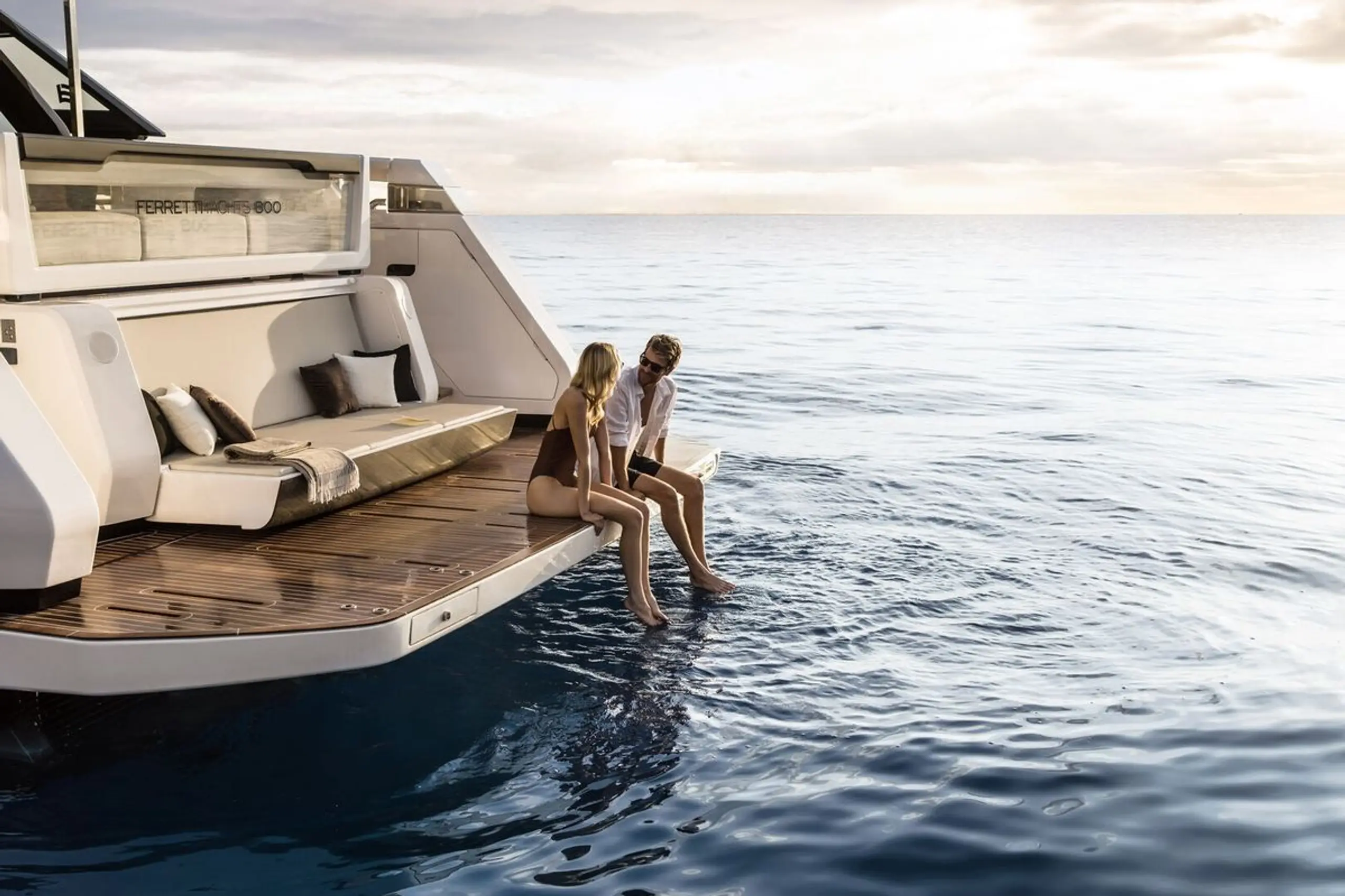 Couple sitting on the swim platform of a yacht at sea.