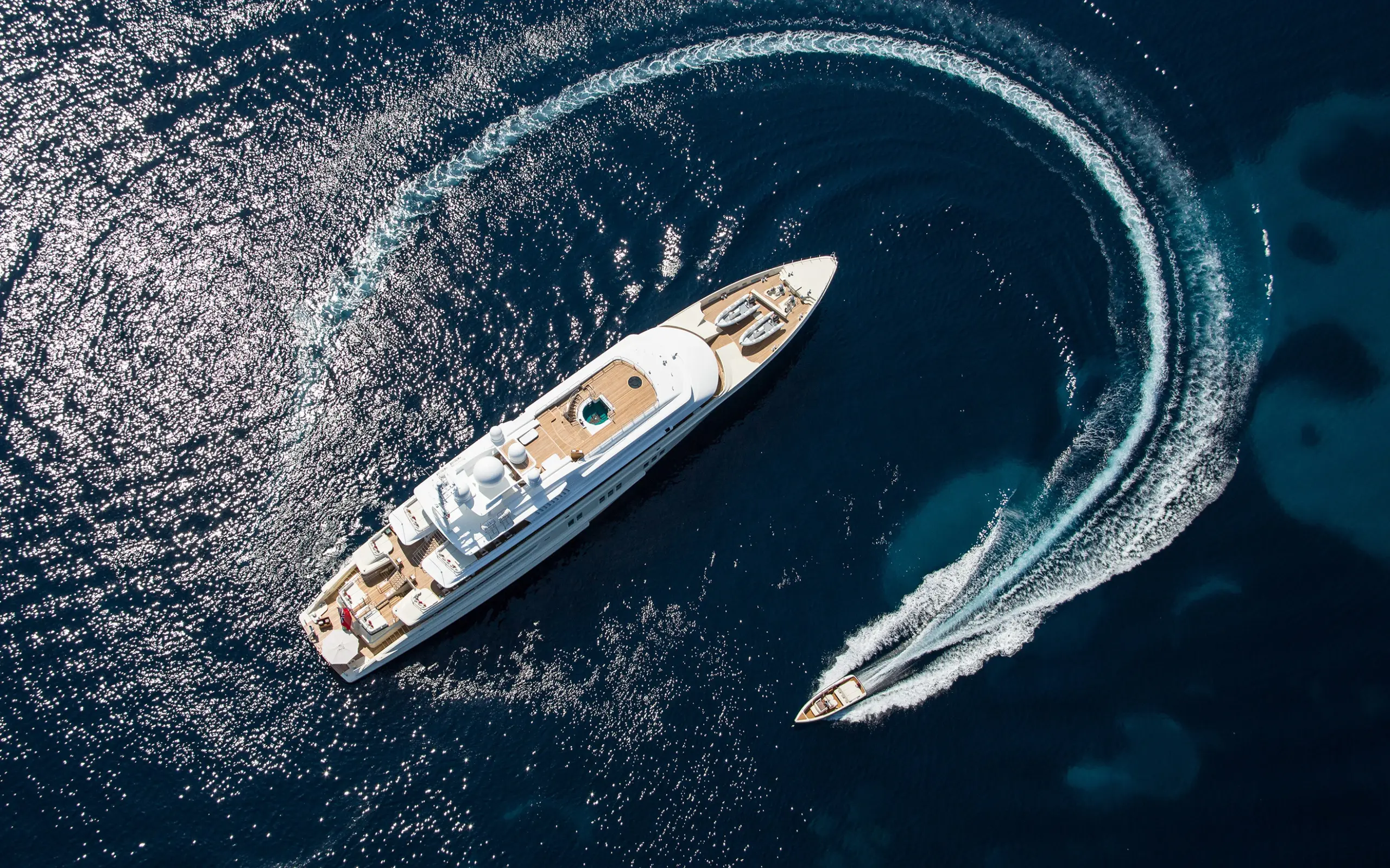 Luxury superyacht anchored off a rocky Mediterranean coastline