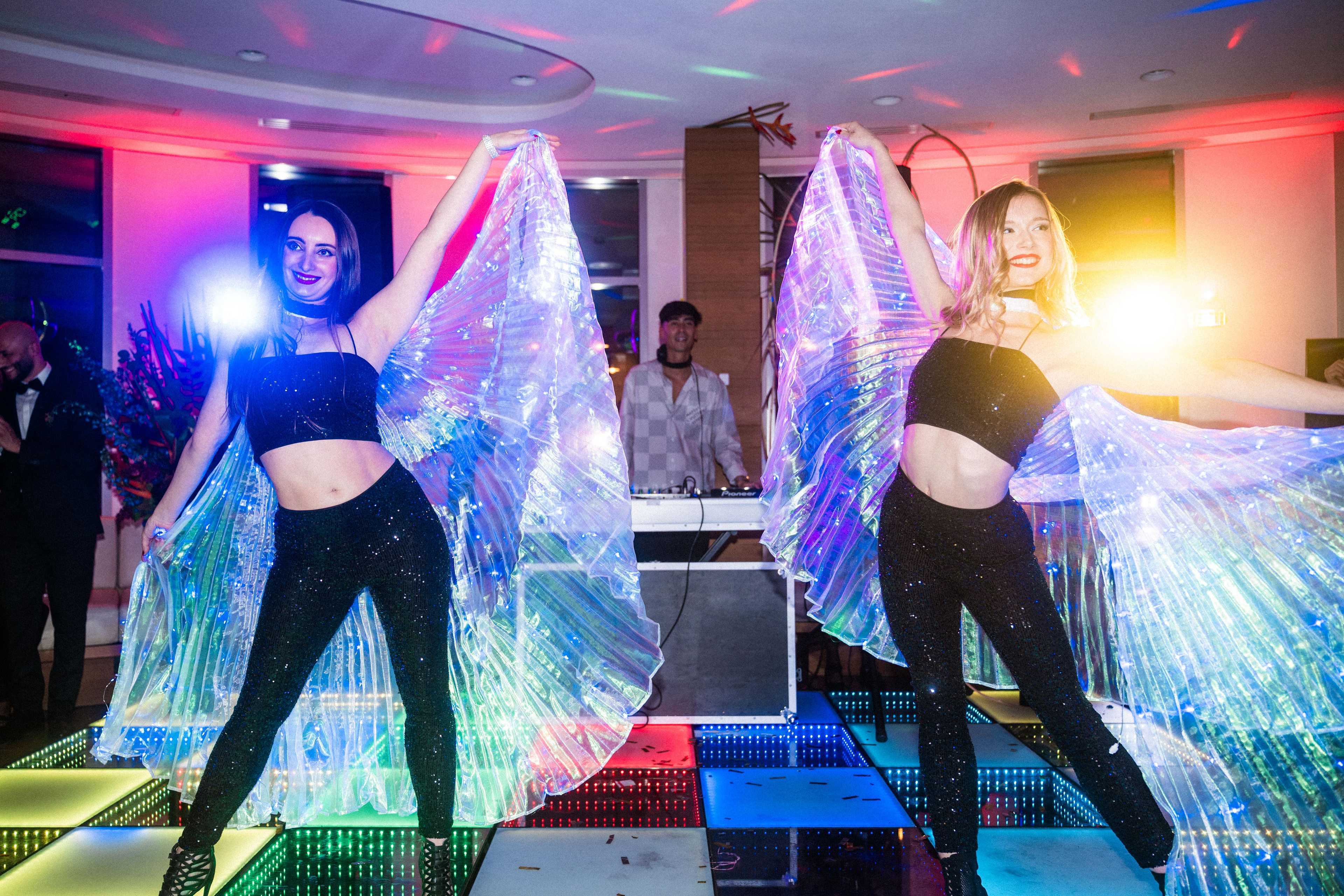 Deux danseuses aux ailes LED sur une piste de danse lumineuse