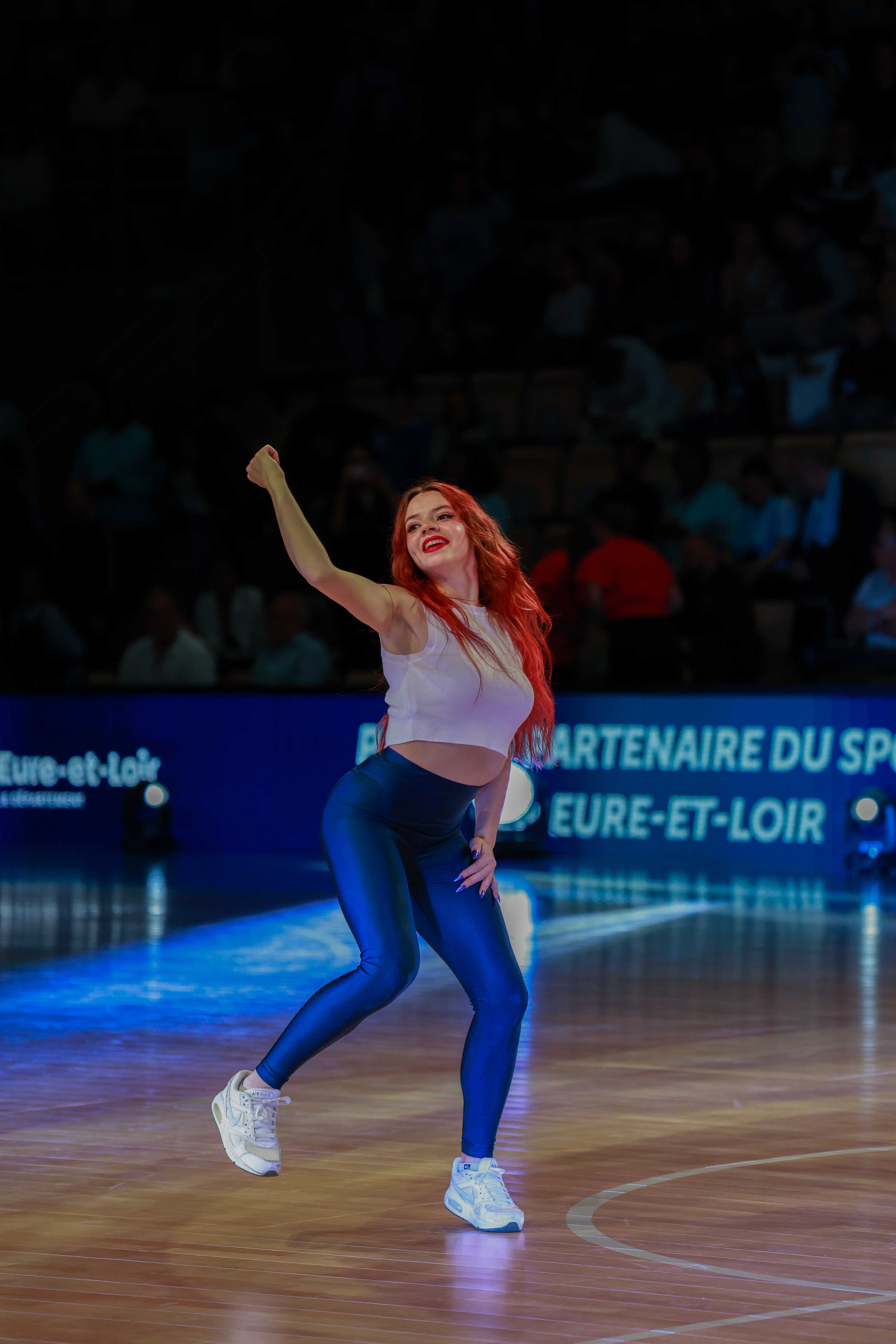 Danseuse poing levé en fin de chorégraphie sur un terrain de basket
