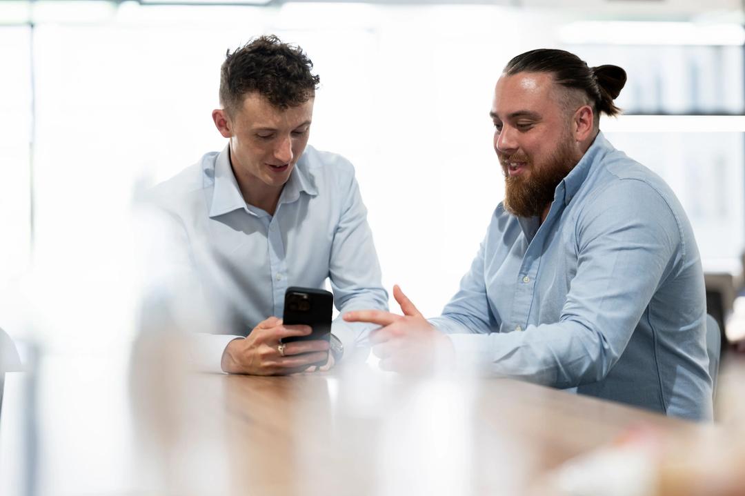 Two male digital marketing experts pointing at phone.