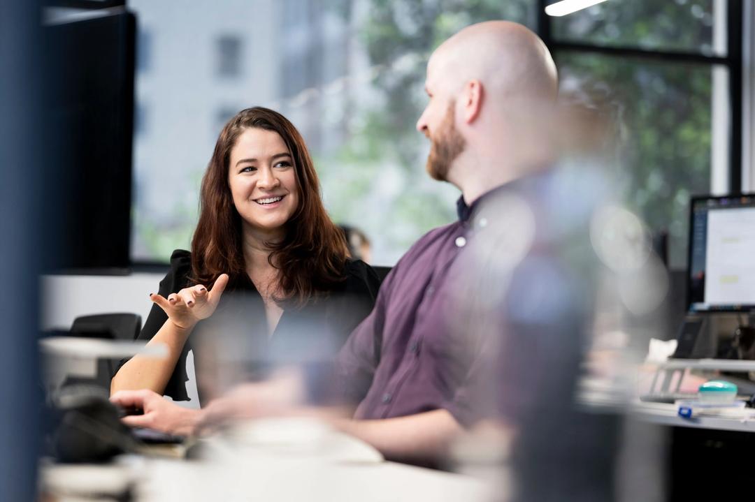 Digital marketing expert explaining web design project to male colleague in office.