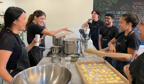 Indago team laughs around table while making ravioli at Italian Cooking School in Marrickville