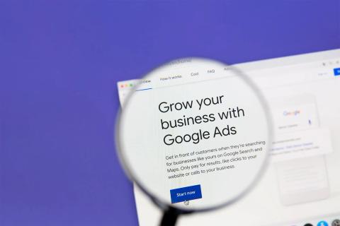 Magnifying glass over webpage: Grow your business with Google Ads. 