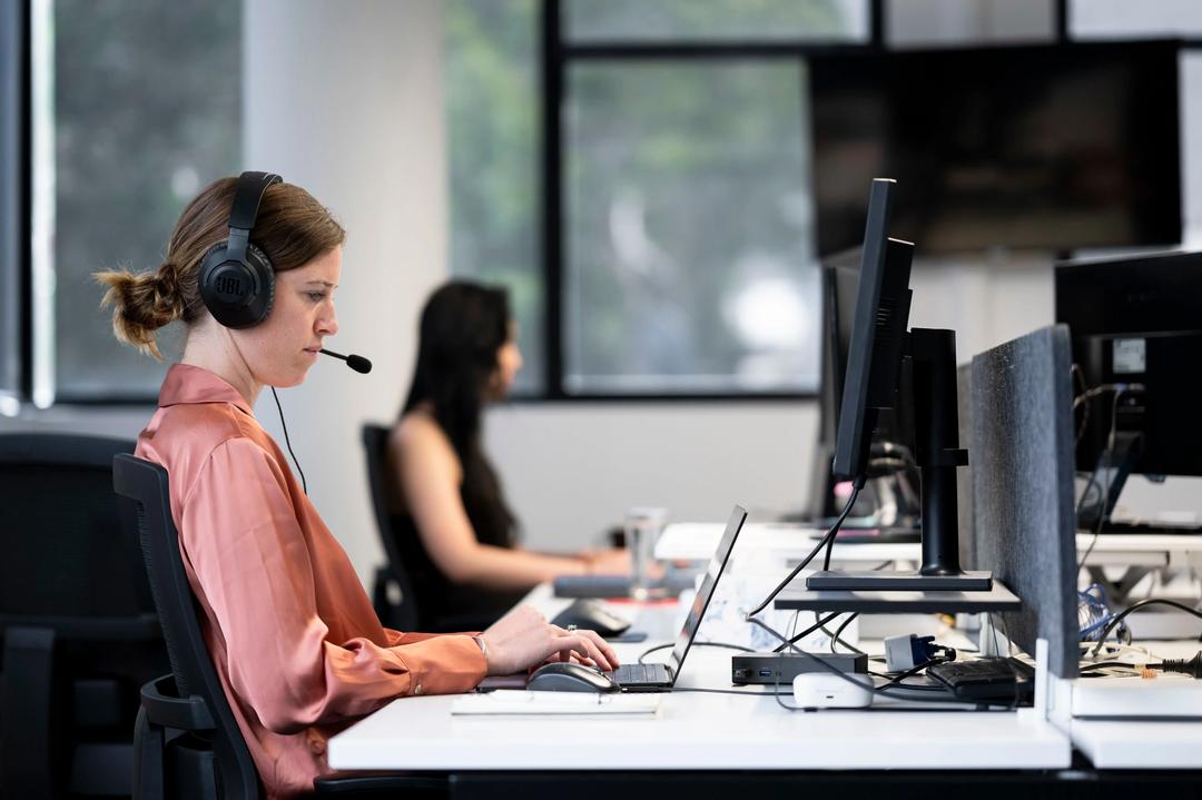 Female international SEO expert with headset working at agency office.