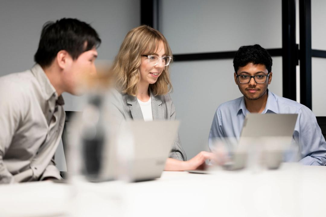 three seo experts looking at a keyword research strategy on a laptop.