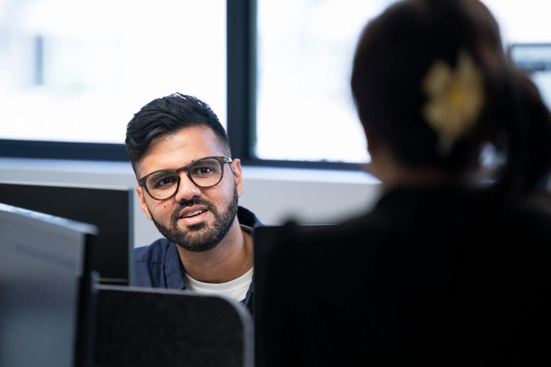 Male specialist at web analytics agency talking to female colleague.