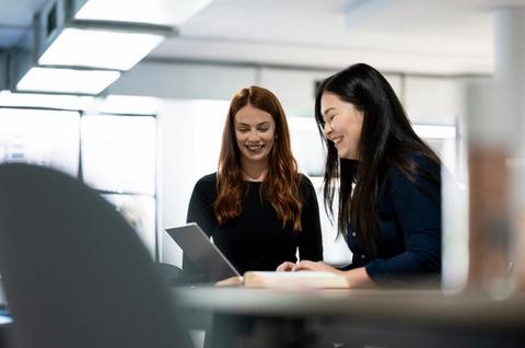 Two female Indago employees smiling at laptop