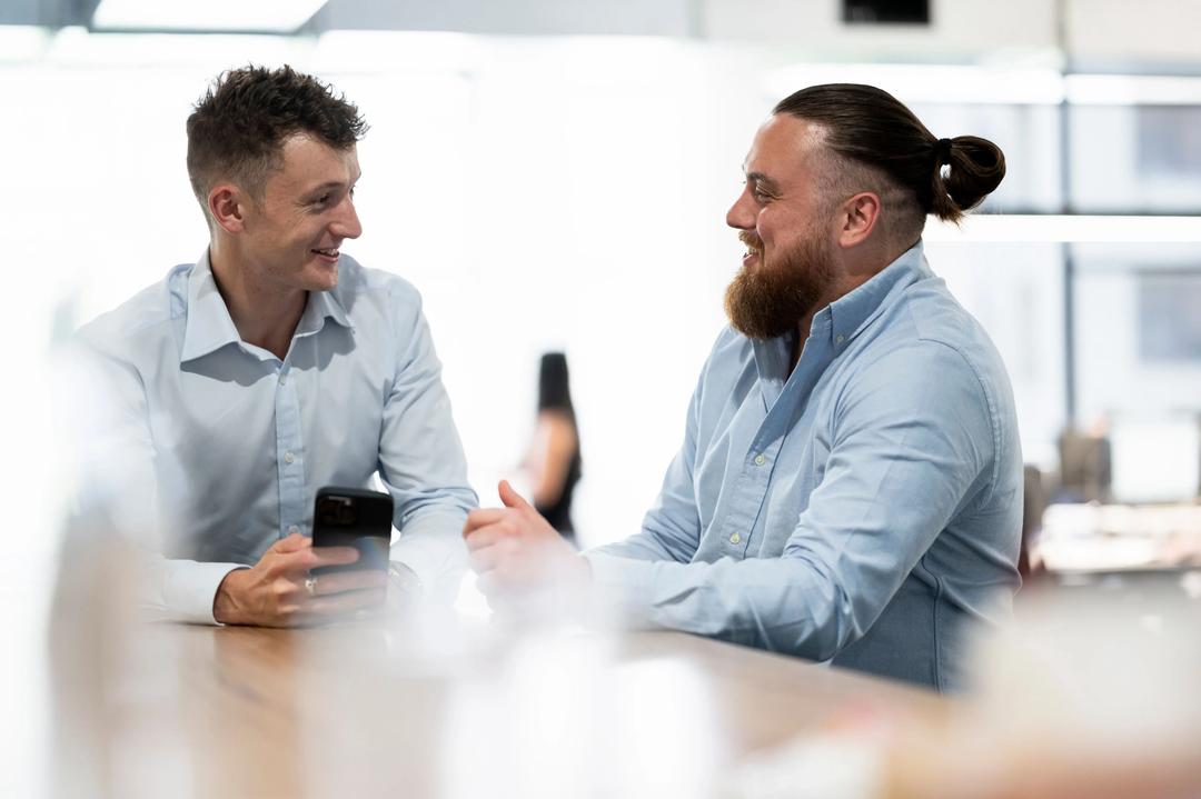 Two male digital marketing experts laughing at phone at a Google Ads Agency office.