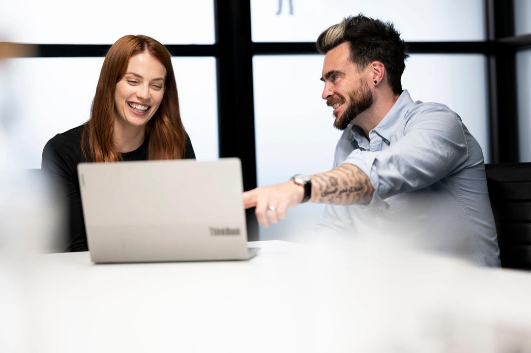 Female seo expert laughing at male collegue pointing at screen