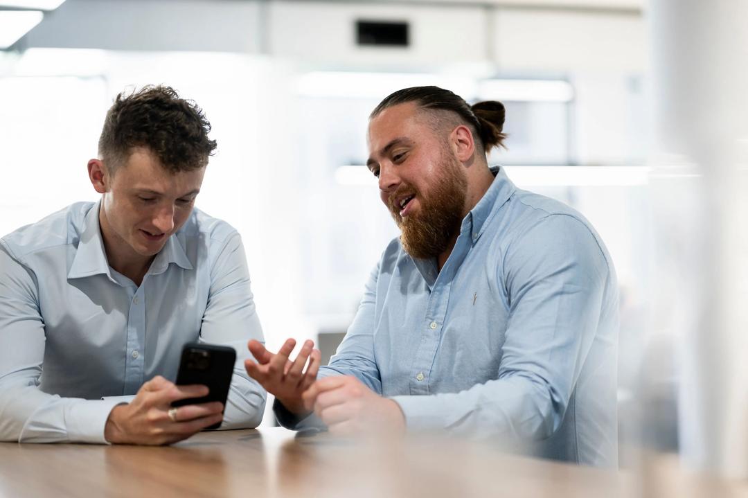Two meta ads experts looking at phone at Facebook advertising agency.