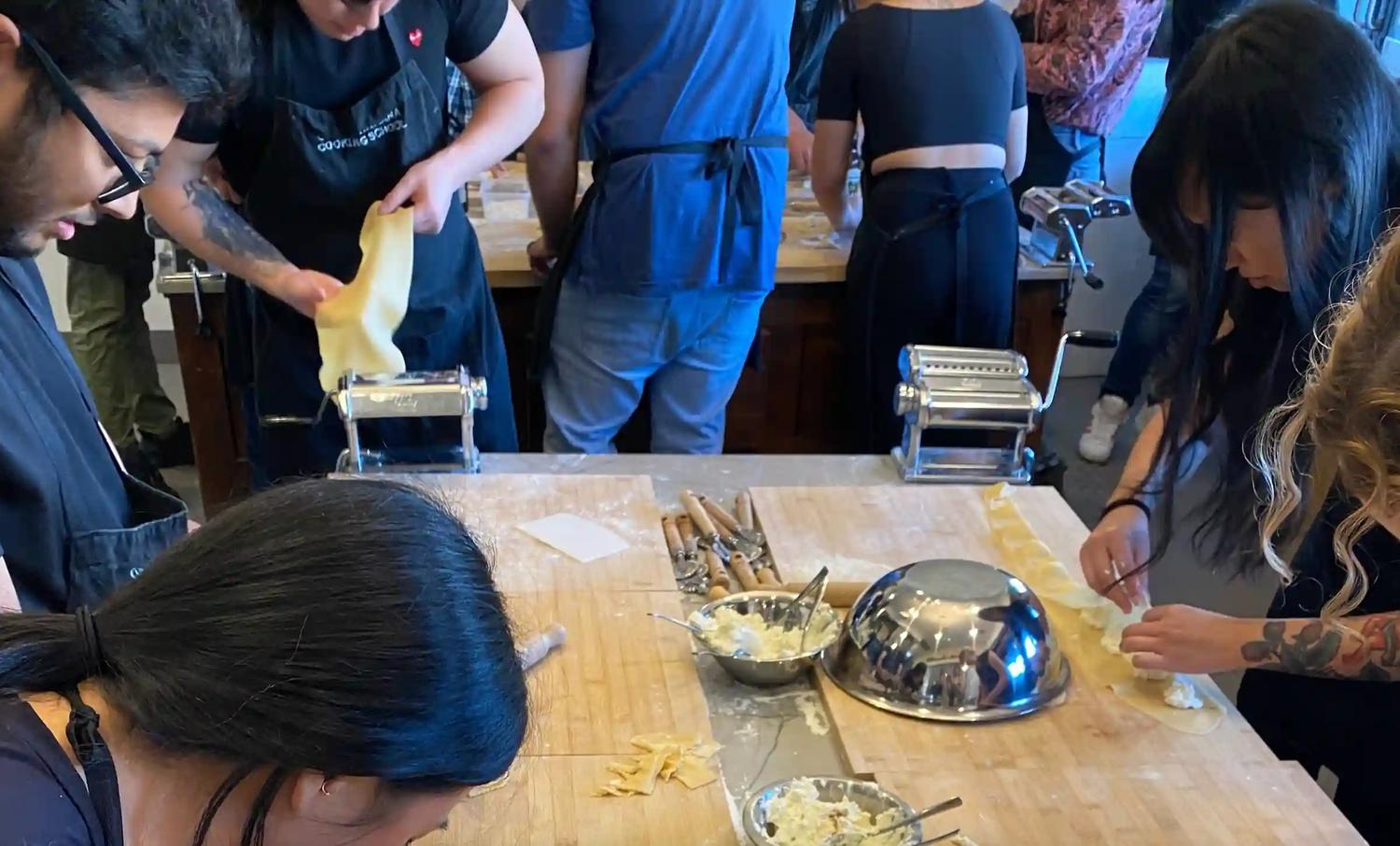 Indago employees roll pasta and make ravioli around a table at an Italian cooking school