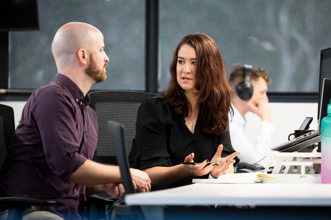 Female paid media performance expert consulting male colleague.