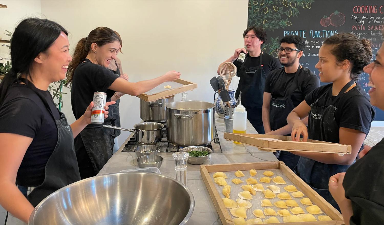 Indago team laughs around table while making ravioli at Italian Cooking School in Marrickville