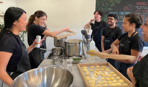 Indago team laughs around table while making ravioli at Italian Cooking School in Marrickville