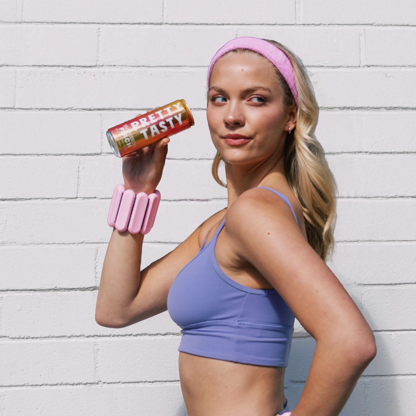 Woman in workout clothes and wrist weights holding up a can of Pretty Tasty Peach