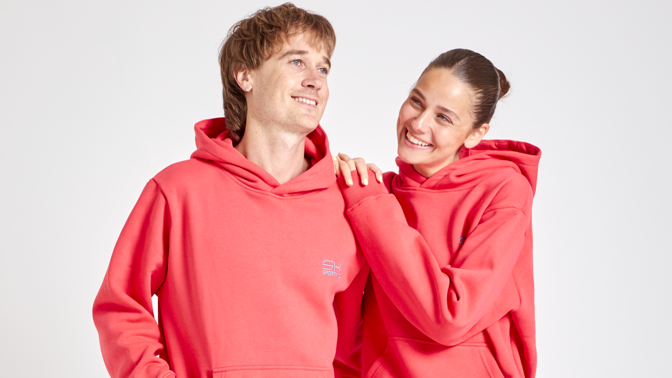 Eine Frauen und ein Mann in pfirsichfarbenen Sportkind Outfits 