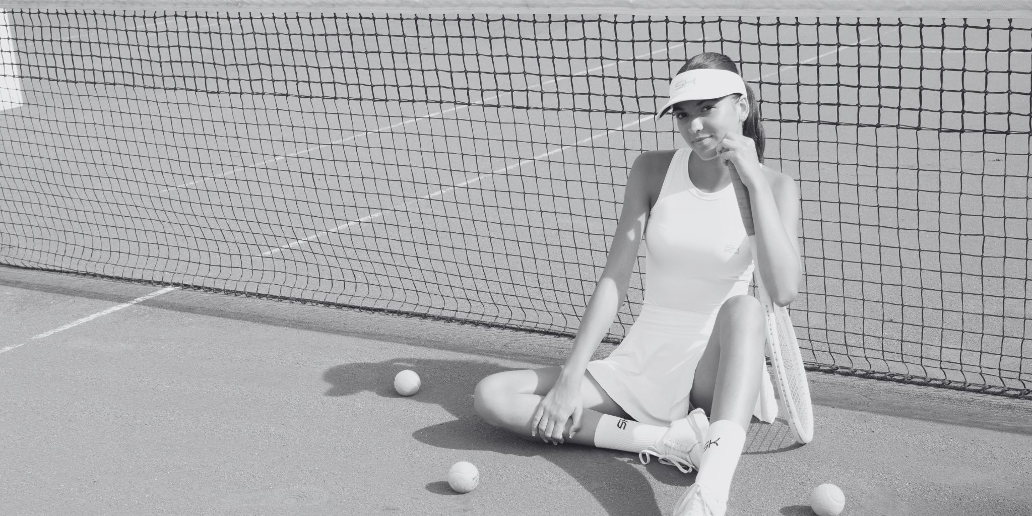 Eine Frau in weißem Sportkind Outfit auf einem Tennisplatz