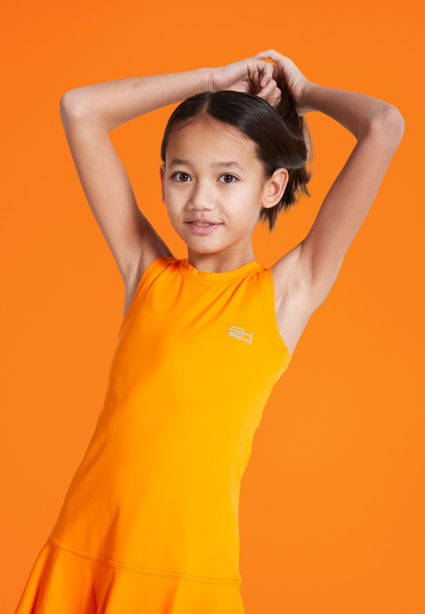 Mädchen im orangenen SPORTKIND Outfit