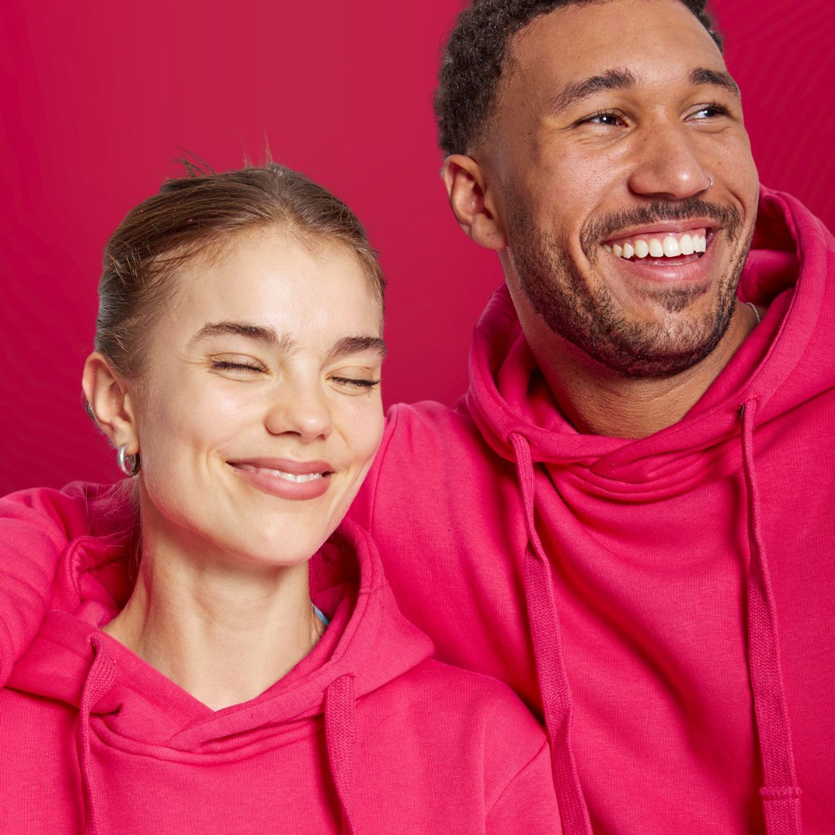 Fröhliches Paar lacht in pinkem SPORTKIND Hoodie