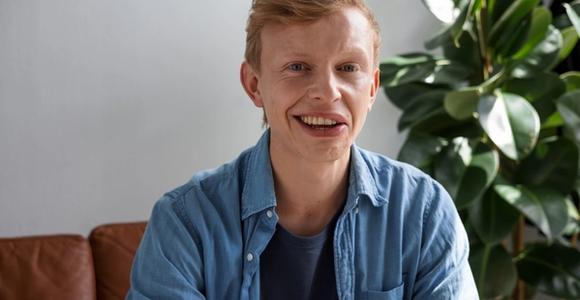 Junger Mann mit Synkinesien lächelt charmant