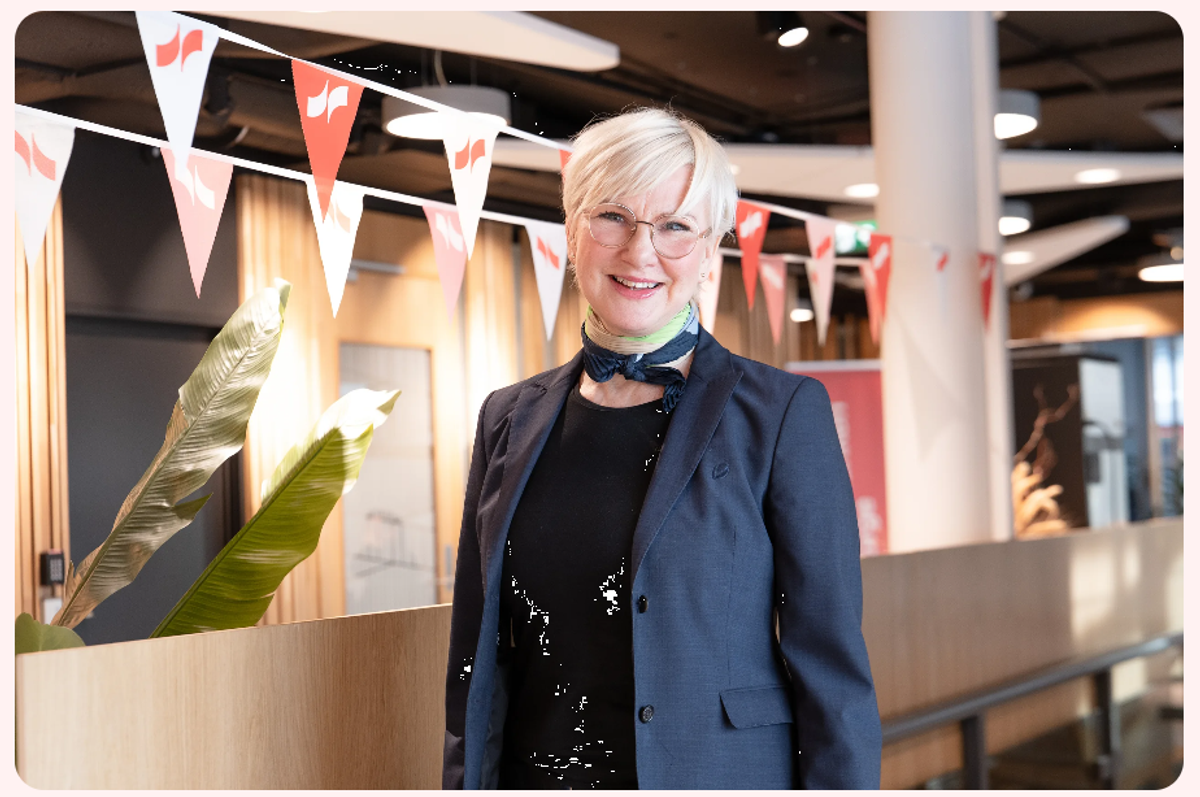 Kvinnelig rådgiver står oppstilt i kontorlandskap og smiler