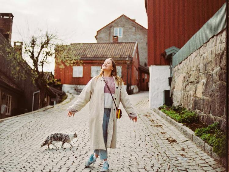 Kvinne som poserer i en bakgårdsgate en fin høstdag
