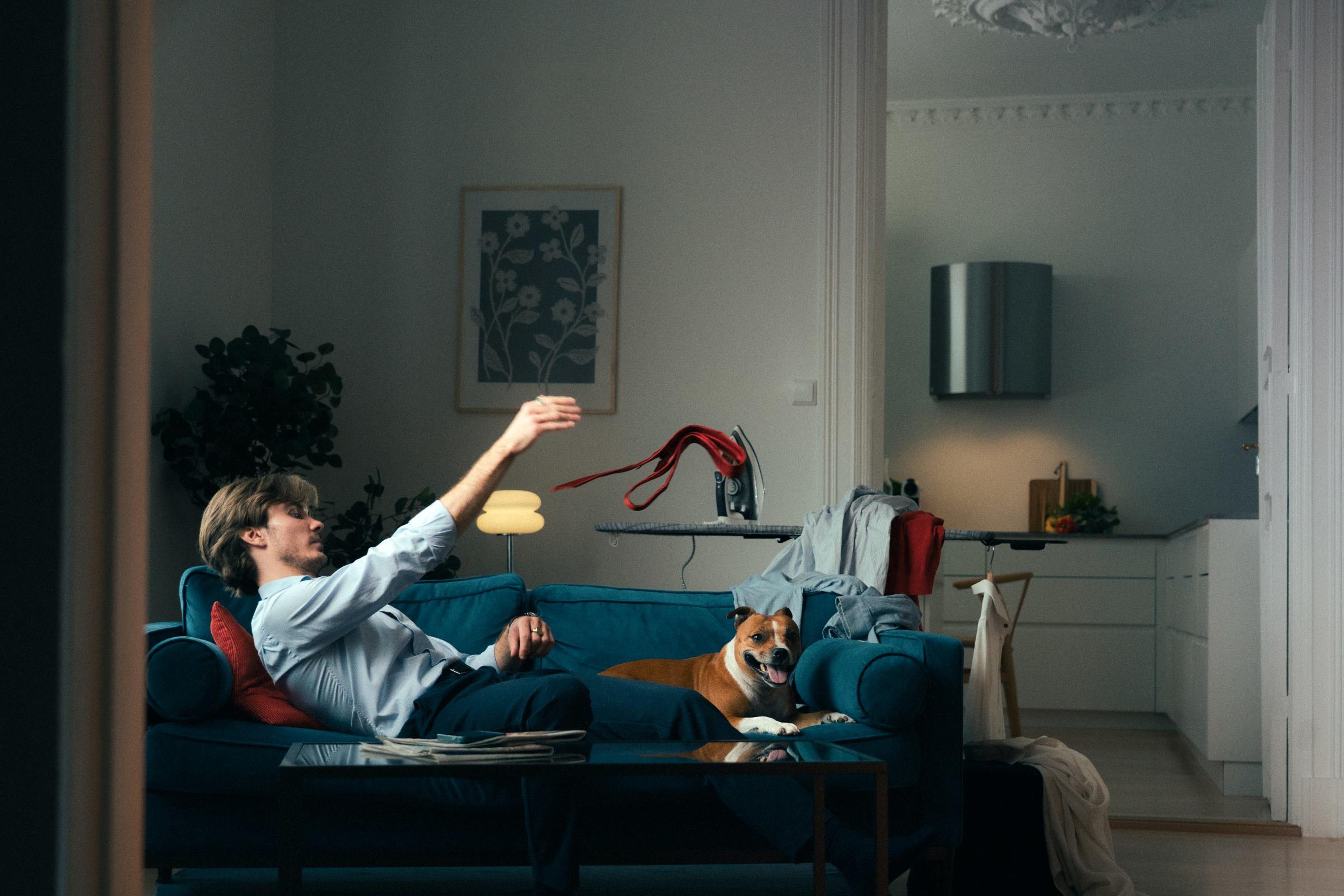 Ung mann som hviler på sofa sammen med en hund