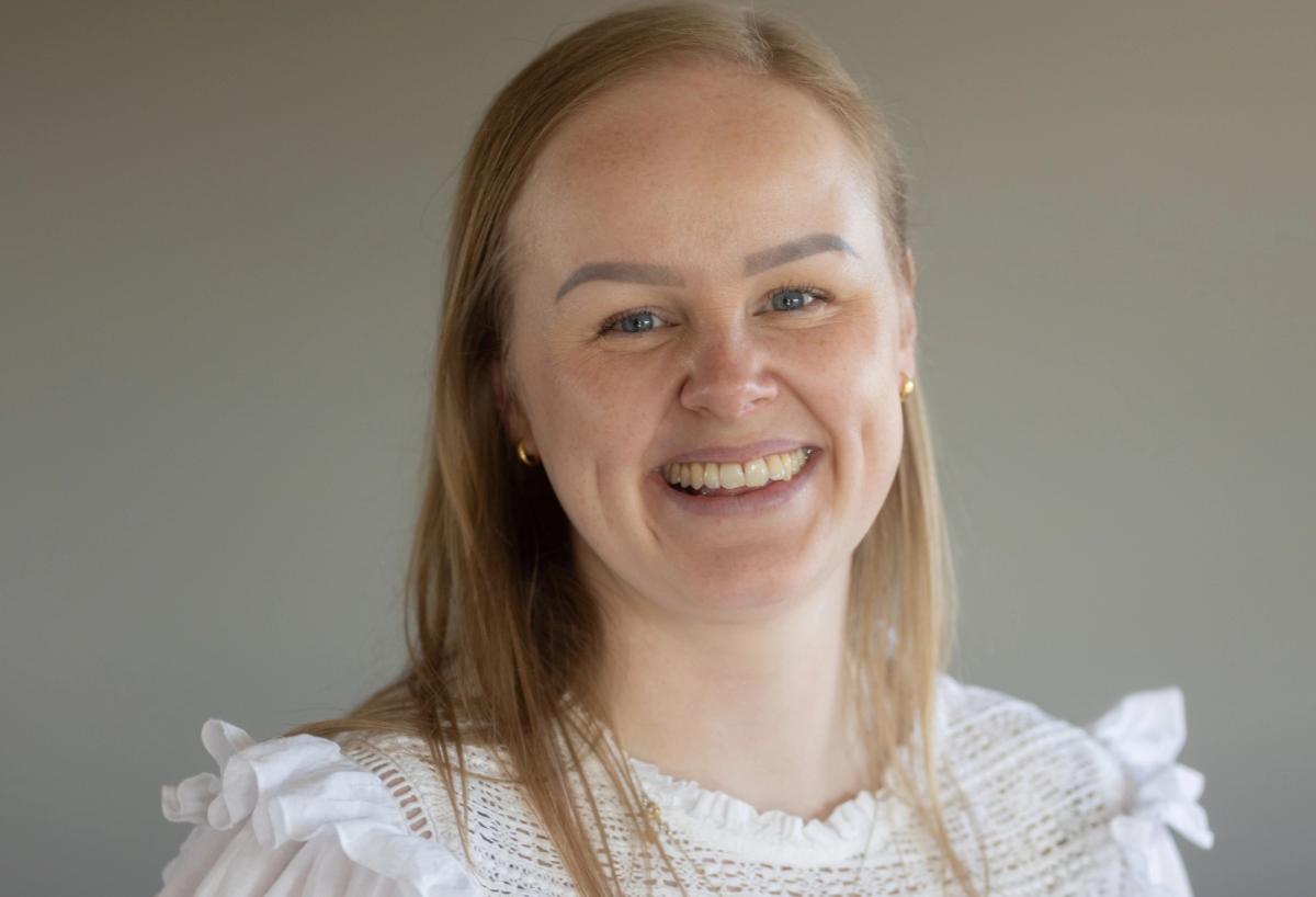 Ung kvinne som smiler med nøytral bakgrunn