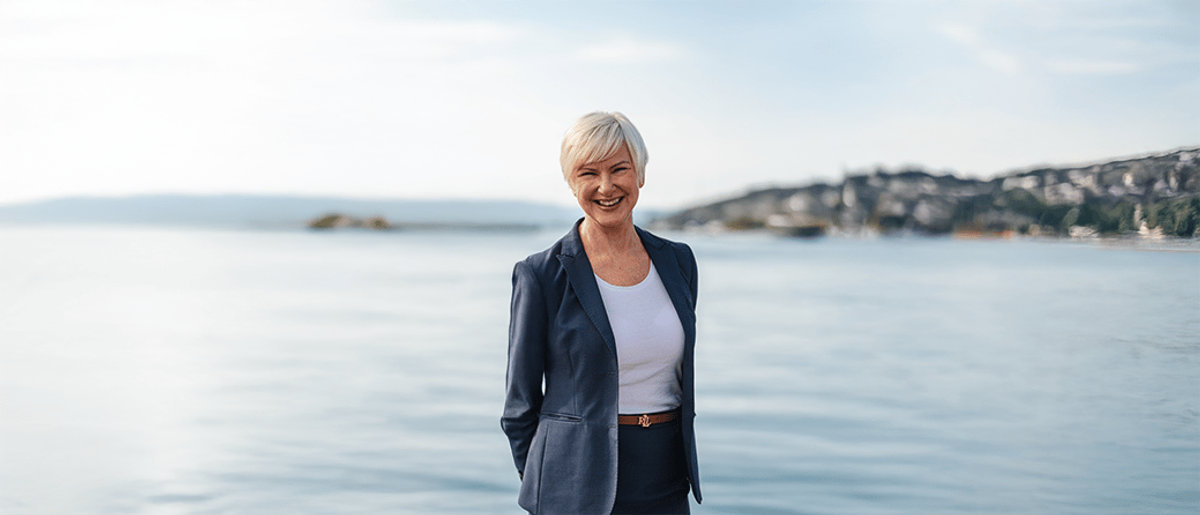 Rådgiver som står oppstilt foran et hav og smiler