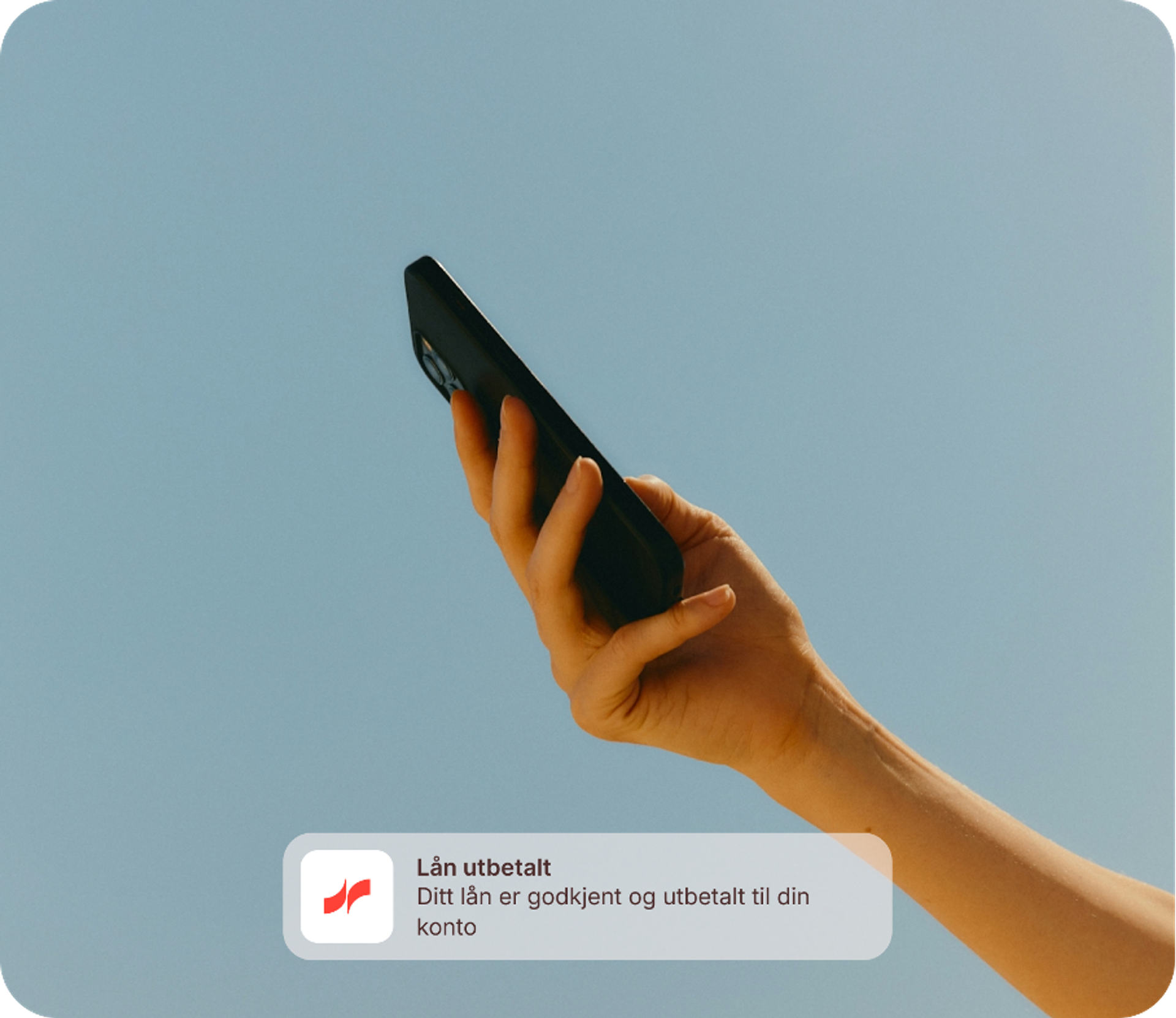 Hånd som holder mobiltelefon opp mot himmelen på en solskinnsdag med en notifikasjon om at lån er utbetalt