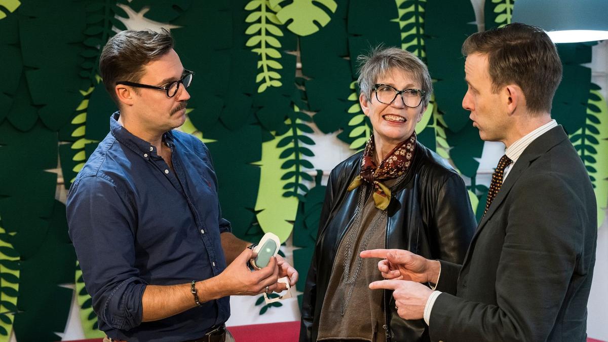 To menn og en kvinne foran grønn bakgrunn.