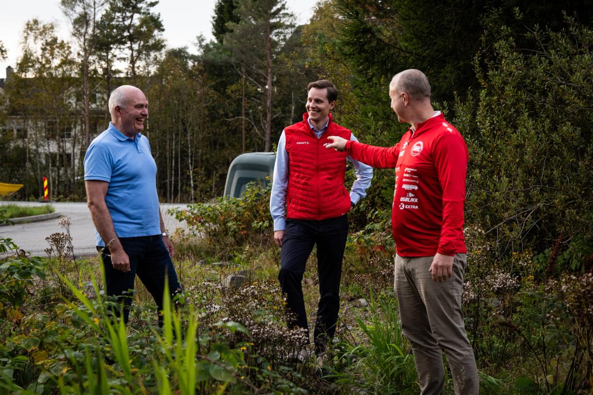 Bilde av tre smilende men som står i skogslig område.