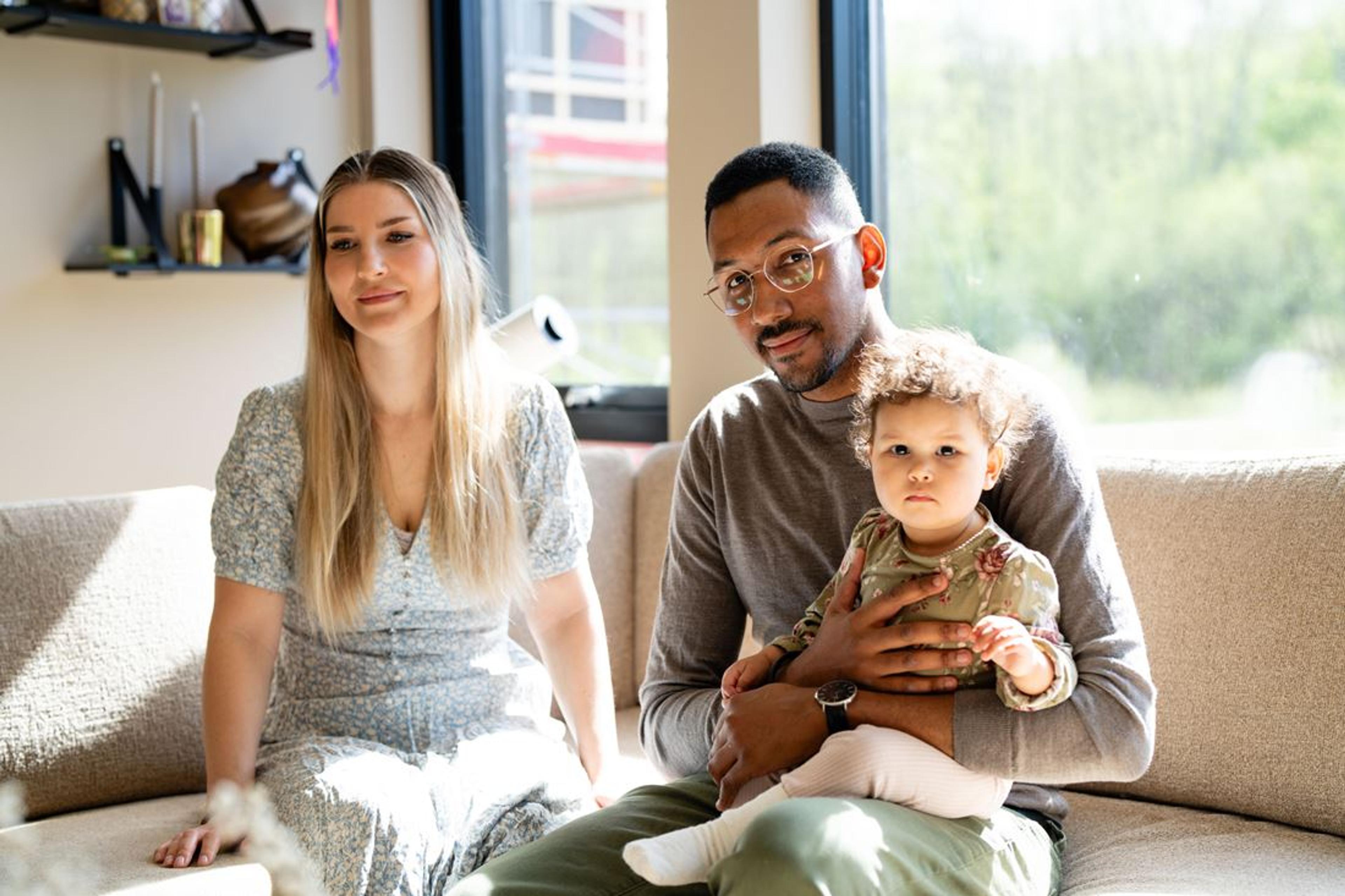 Familie på tre som sitter i sofa