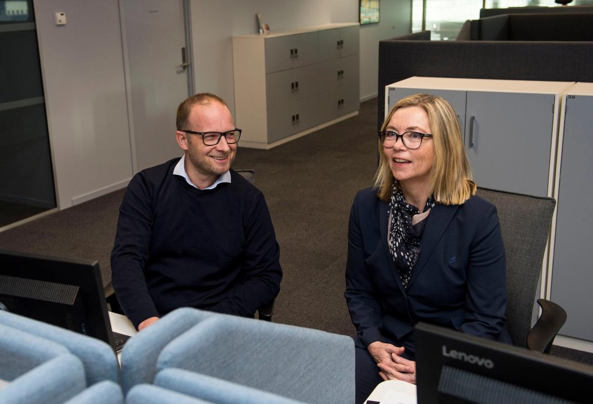 To rådgivere, mann og kvinne, som sitter i kontorlandskap