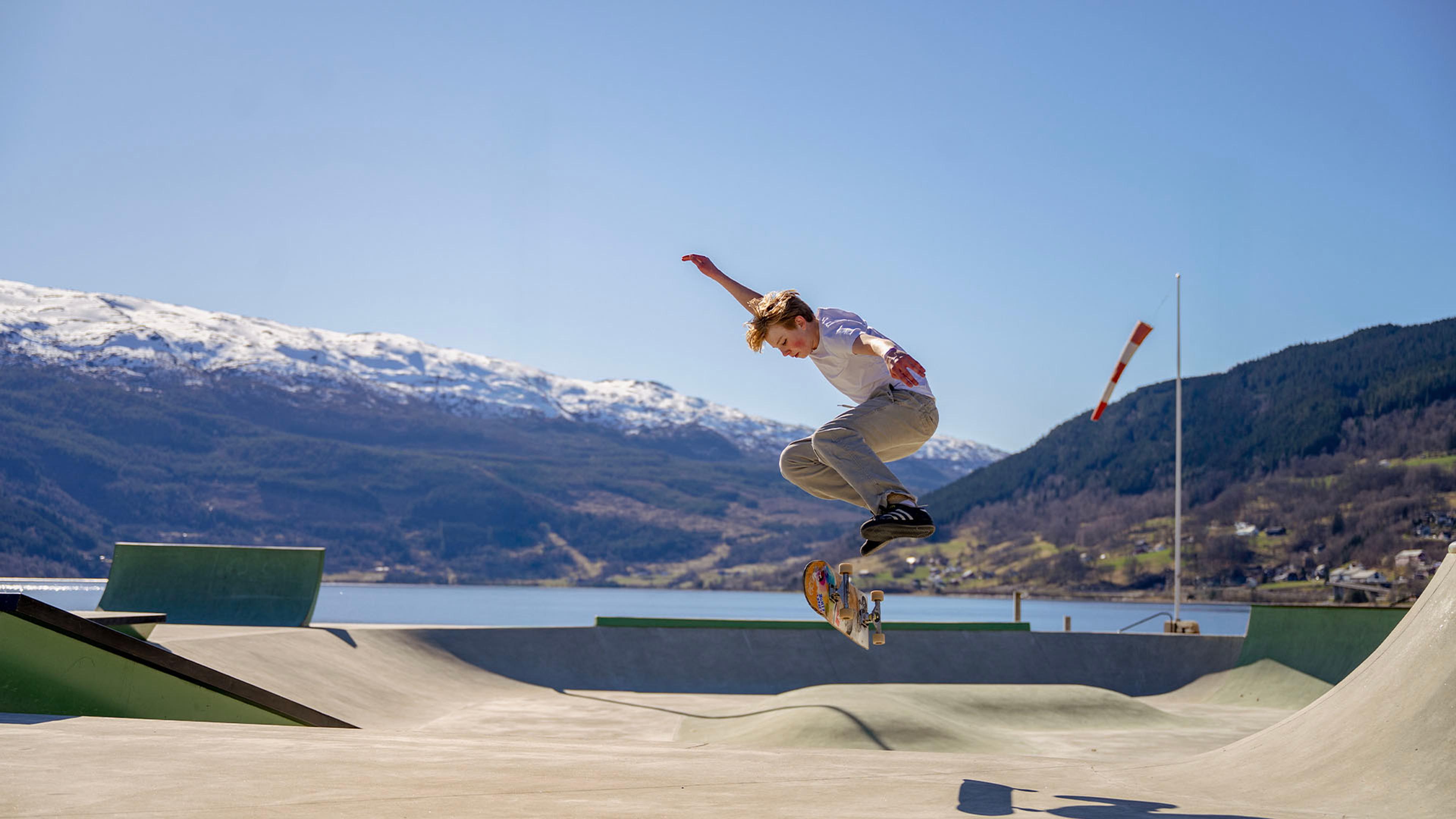 Gutt som skater i rampe med fjell og fjord i bakgrunnen