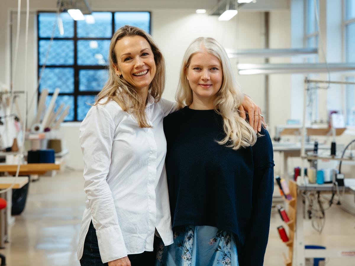 To kvinner i et industrilokale med tekstilutstyr i bakgrunnen.