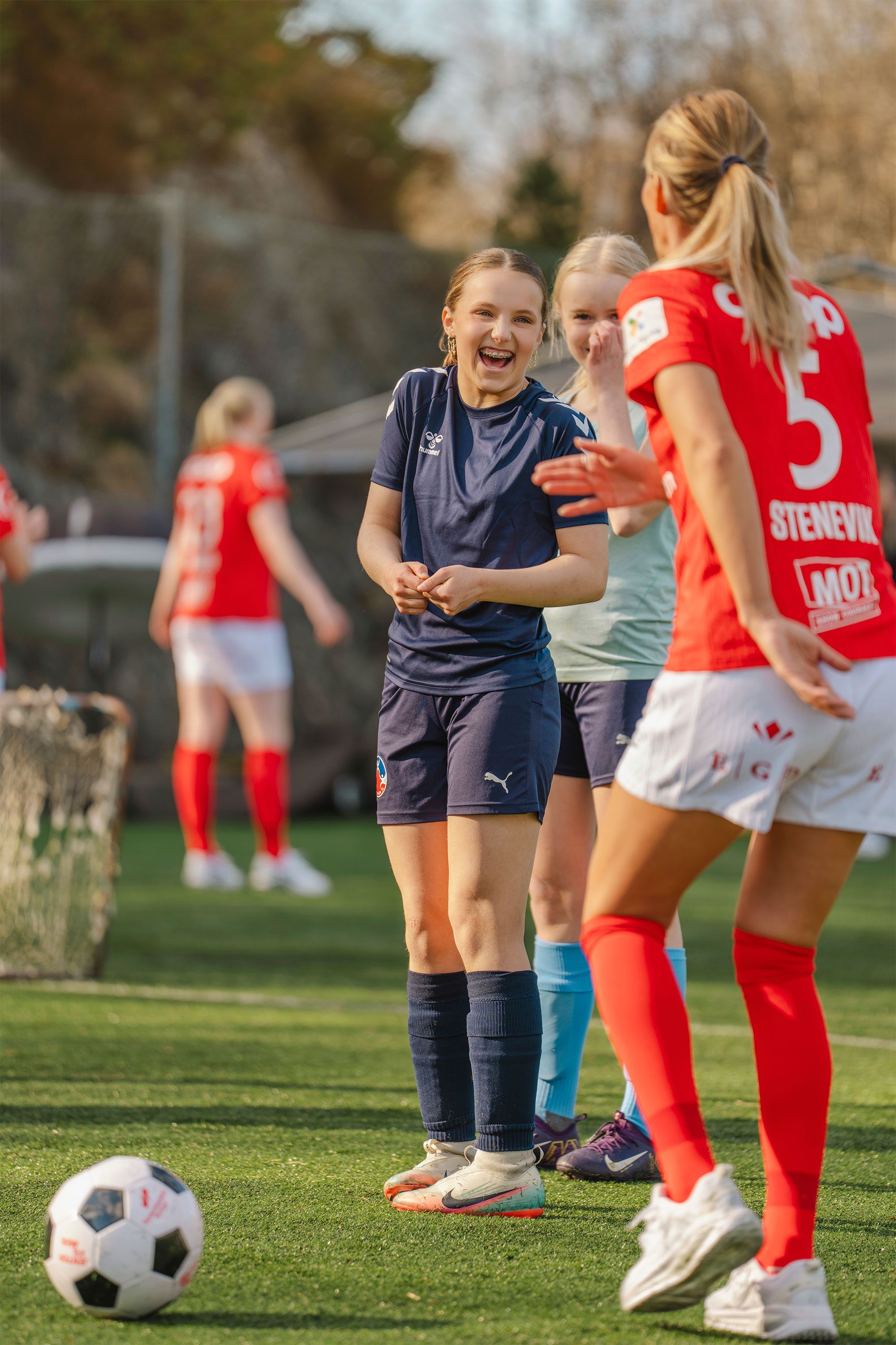 Jenter spiller fotball med en fotballspiller