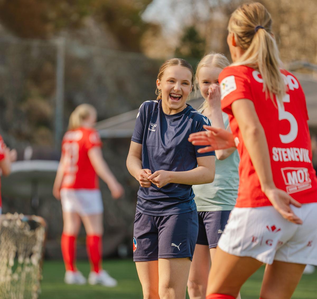 Jenter spiller fotball med en fotballspiller