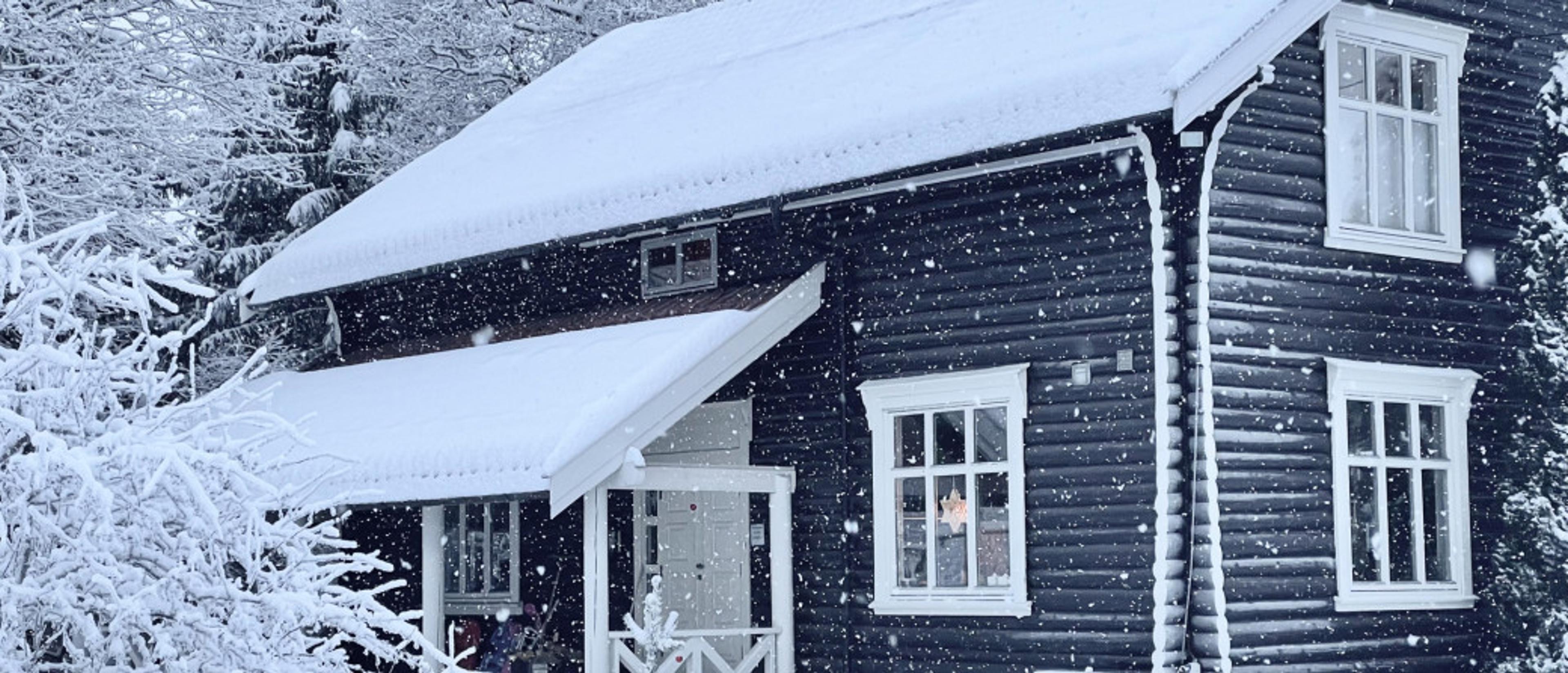 Hytte med snø som daler ned på vinteren