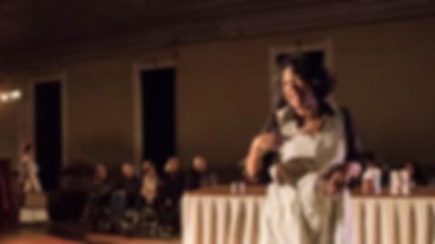 a Black woman in an apron, singing into a wooden spoon