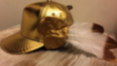 A gold baseball cap, with feathers attached