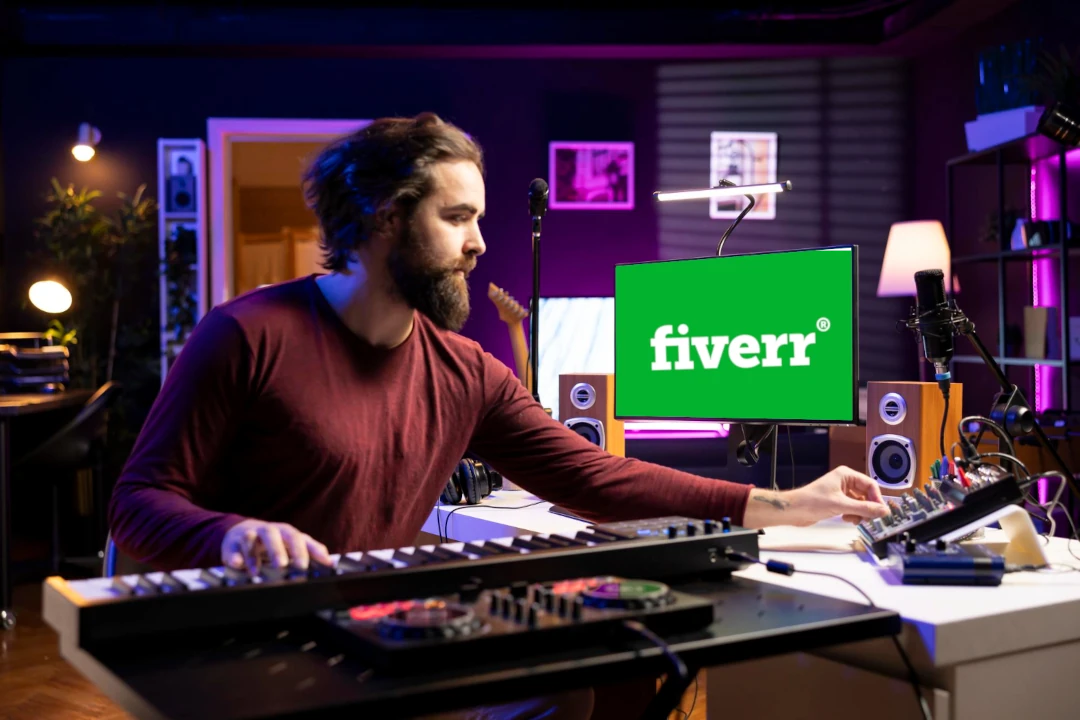 Music producer working on Fiverr gigs from a home studio with a laptop and audio gear.