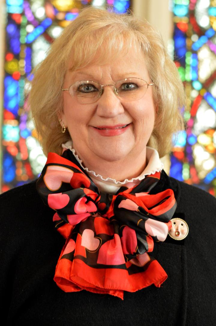 Julie smiles for a staff portrait, with colorful stained glass filling the background.